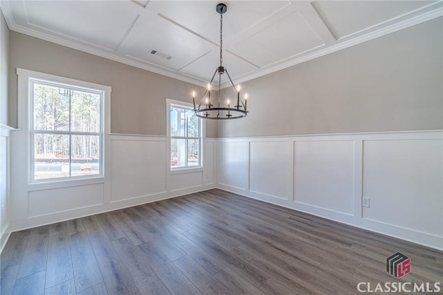 unfurnished dining area featuring dark wood-type flooring, ornamental molding, coffered ceiling, and an inviting chandelier