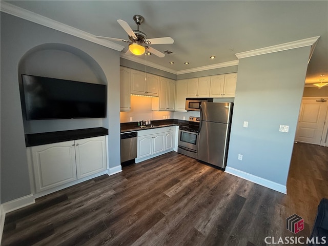 kitchen with dark hardwood / wood-style flooring, stainless steel appliances, white cabinetry, and ornamental molding