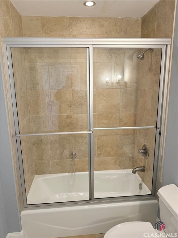 bathroom featuring toilet and combined bath / shower with glass door