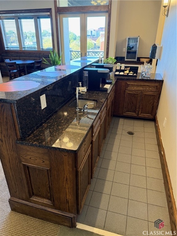 kitchen featuring dark stone countertops, kitchen peninsula, and light tile patterned floors