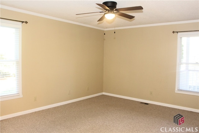 carpeted spare room with baseboards, visible vents, and crown molding