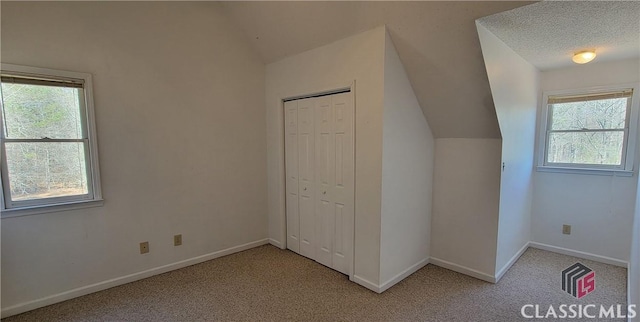 unfurnished bedroom with light carpet, a closet, multiple windows, and vaulted ceiling