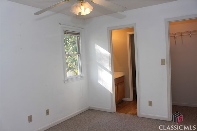 unfurnished bedroom with baseboards, a spacious closet, a closet, and light colored carpet