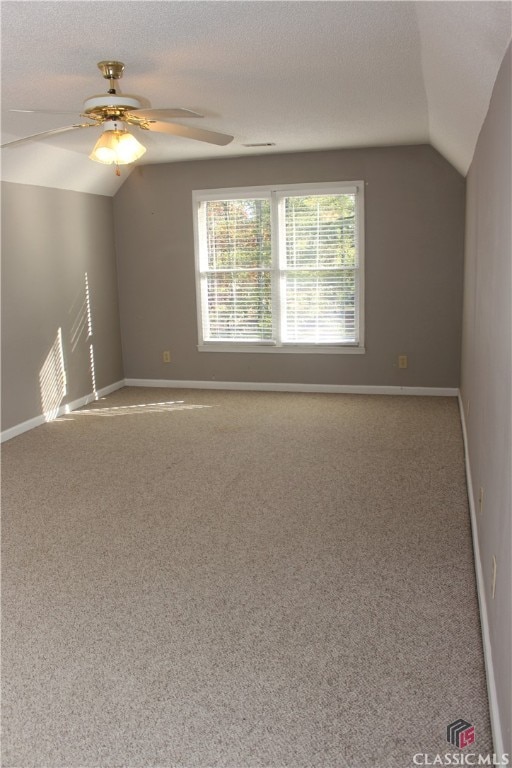 spare room featuring lofted ceiling, baseboards, and a textured ceiling