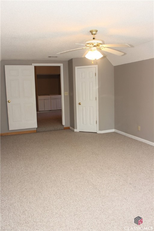 unfurnished room with ceiling fan, a textured ceiling, carpet, and baseboards