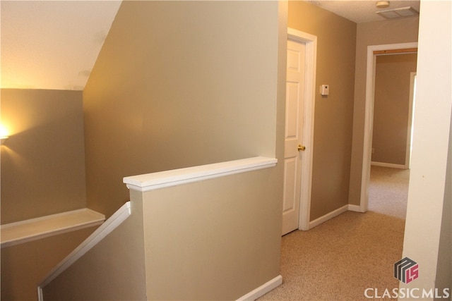 hall featuring baseboards, visible vents, light colored carpet, lofted ceiling, and an upstairs landing