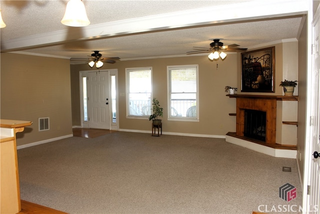 unfurnished living room with crown molding, a textured ceiling, a fireplace with raised hearth, and carpet flooring