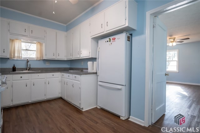 kitchen with a wealth of natural light, white cabinetry, sink, and white refrigerator