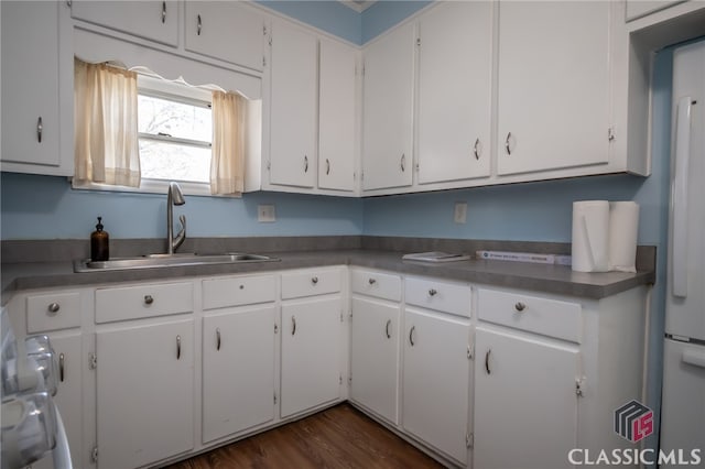 kitchen with stainless steel counters, sink, white cabinets, and dark hardwood / wood-style floors