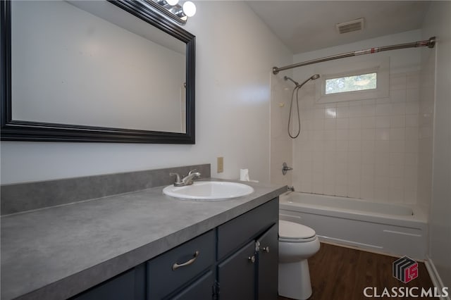 full bathroom featuring hardwood / wood-style flooring, vanity, toilet, and tiled shower / bath