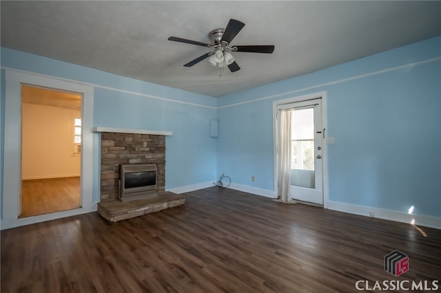 unfurnished living room featuring a stone fireplace, ceiling fan, and dark hardwood / wood-style flooring