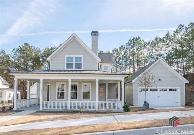 farmhouse featuring a porch, a garage, and an outdoor structure