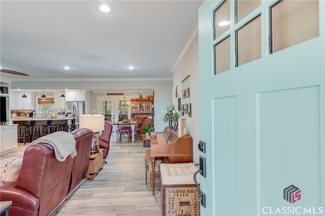 living room featuring light hardwood / wood-style floors, ornamental molding, and french doors