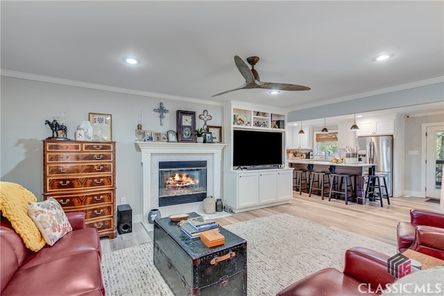 living room featuring ceiling fan, crown molding, and light hardwood / wood-style flooring