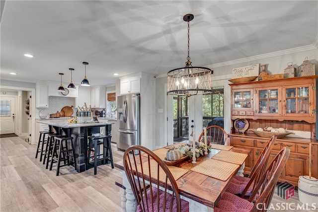 dining area featuring crown molding, french doors, a notable chandelier, and light wood-type flooring