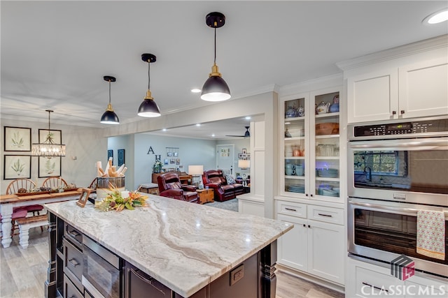 kitchen with white cabinetry, double oven, crown molding, pendant lighting, and light hardwood / wood-style floors