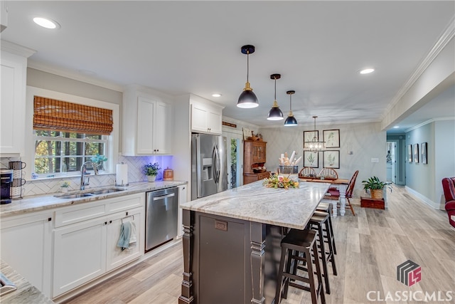 kitchen with white cabinetry, sink, light hardwood / wood-style floors, a kitchen island, and appliances with stainless steel finishes