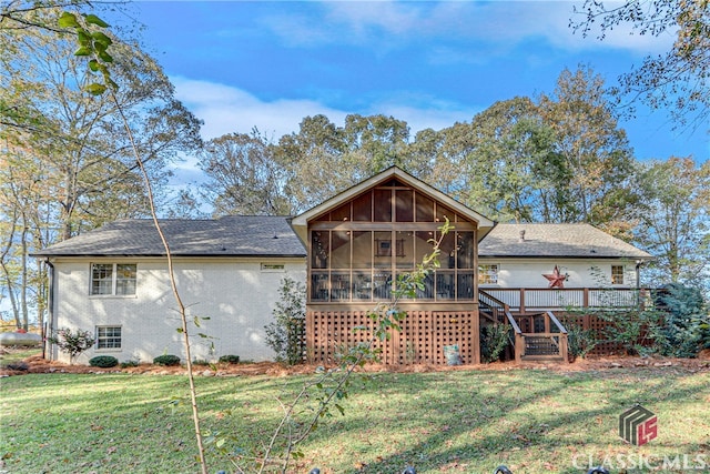 rear view of property with a deck, a lawn, and a sunroom