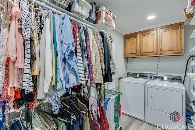 washroom featuring cabinets, independent washer and dryer, light hardwood / wood-style floors, and ornamental molding