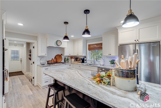 kitchen with light stone countertops, sink, pendant lighting, white cabinets, and appliances with stainless steel finishes