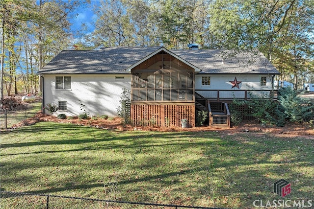 rear view of house with a yard, a wooden deck, and a sunroom