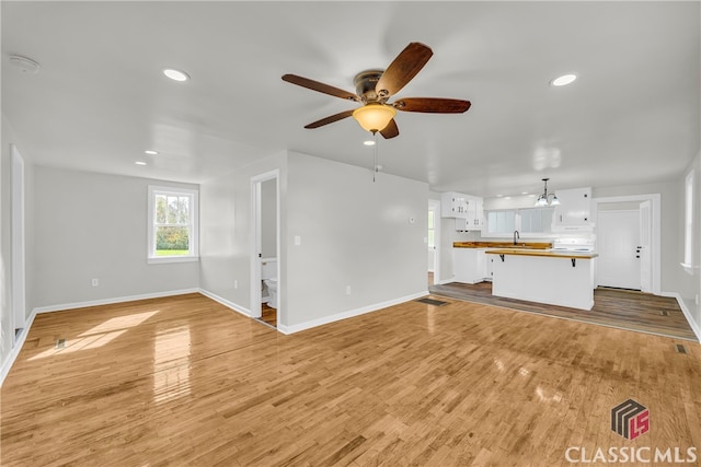 unfurnished living room featuring ceiling fan and light wood-type flooring