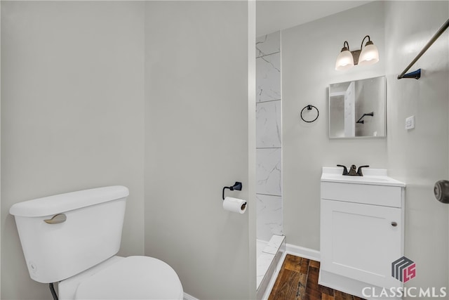 bathroom featuring hardwood / wood-style floors, vanity, toilet, and walk in shower