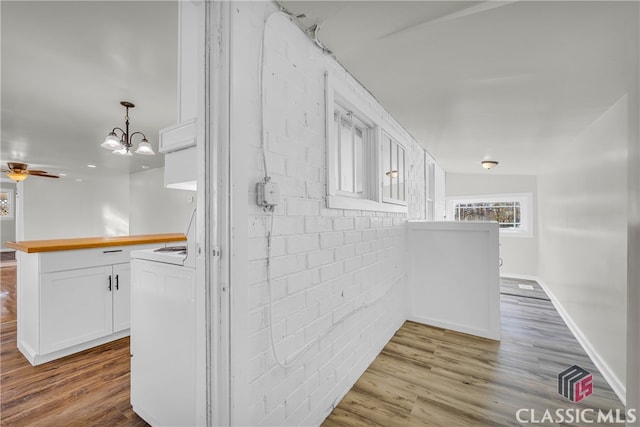 hall featuring light hardwood / wood-style flooring, brick wall, and a notable chandelier