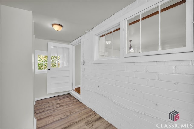 entryway with brick wall and hardwood / wood-style flooring