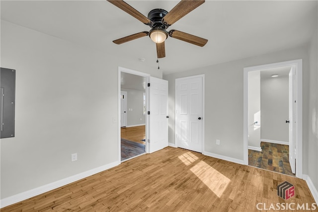 unfurnished bedroom featuring electric panel, hardwood / wood-style flooring, and ceiling fan