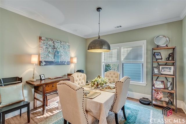 dining area featuring light wood-type flooring and ornamental molding