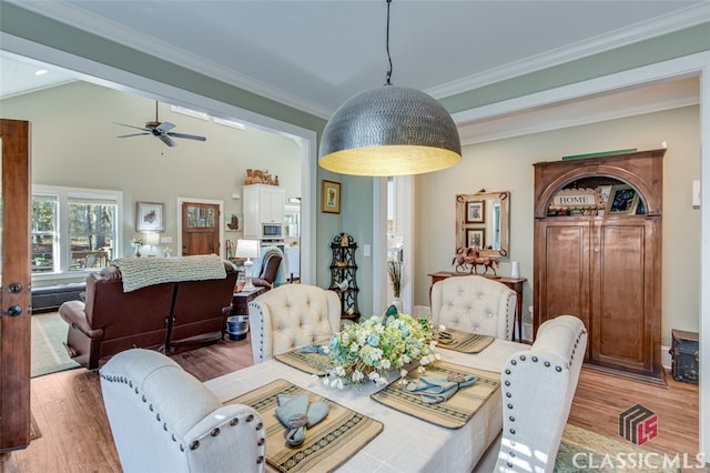 dining space with lofted ceiling, ceiling fan, wood-type flooring, and ornamental molding