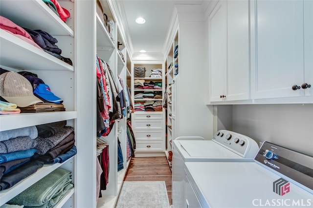 washroom with cabinets, light hardwood / wood-style flooring, washer and clothes dryer, and ornamental molding