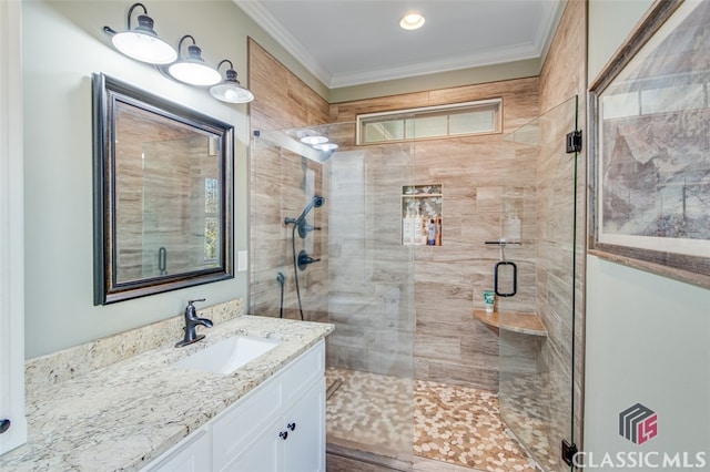 bathroom featuring a shower with shower door, ornamental molding, and vanity