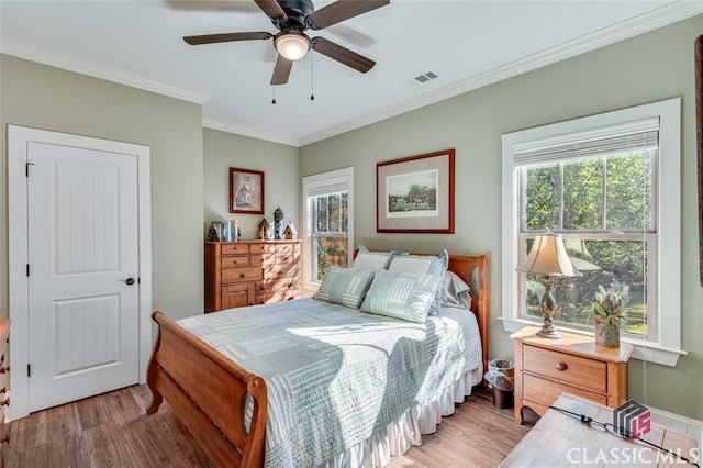 bedroom with multiple windows, hardwood / wood-style floors, ceiling fan, and crown molding