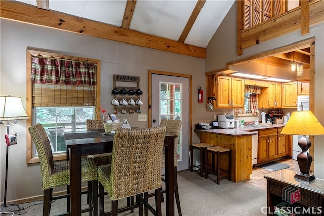 carpeted dining space with lofted ceiling with beams and sink