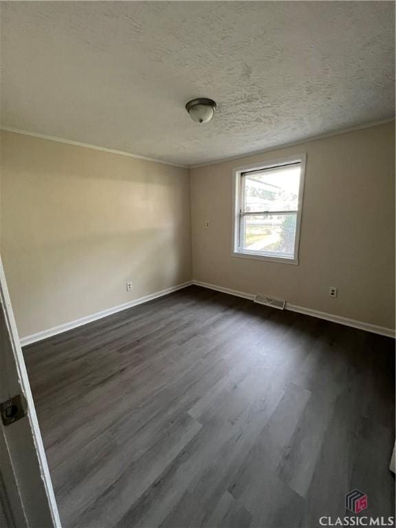 spare room featuring a textured ceiling, dark hardwood / wood-style floors, and ornamental molding