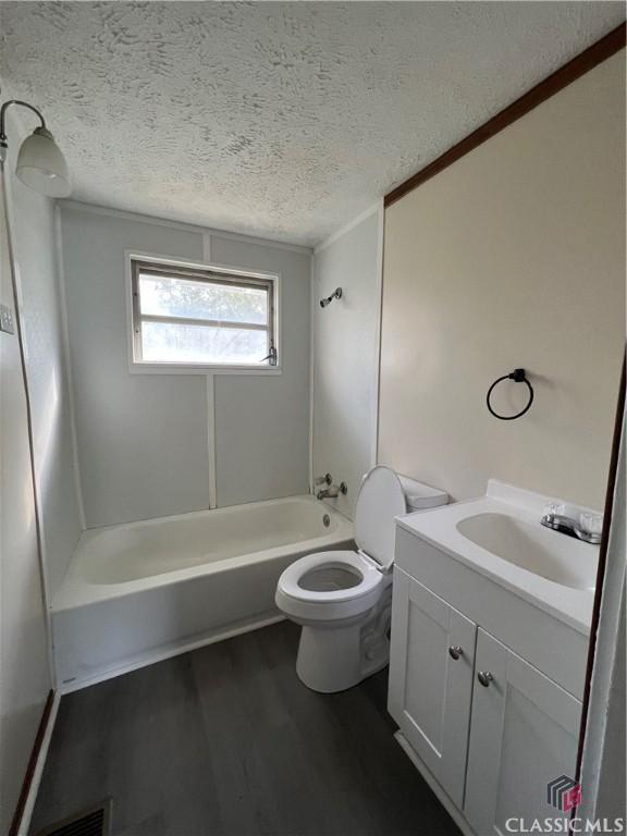 full bathroom featuring shower / bathing tub combination, vanity, toilet, a textured ceiling, and wood-type flooring