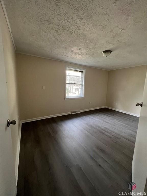 spare room featuring a textured ceiling, ornamental molding, and dark wood-type flooring