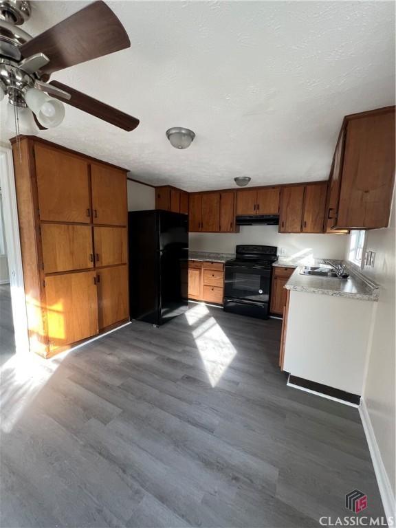 kitchen with black appliances, ceiling fan, sink, and hardwood / wood-style flooring