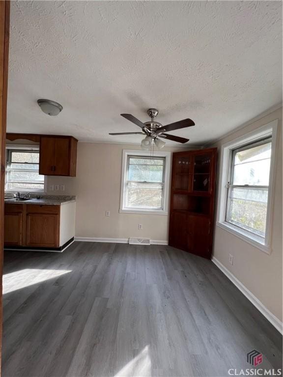 unfurnished living room featuring hardwood / wood-style flooring, a textured ceiling, and a wealth of natural light