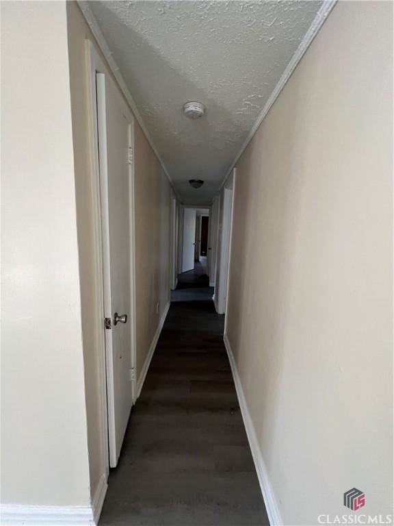 hallway with a textured ceiling and dark hardwood / wood-style floors