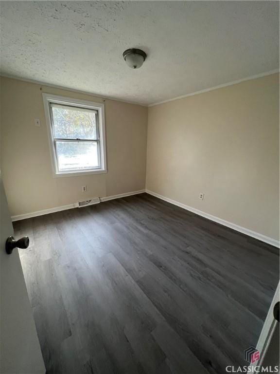 empty room with dark hardwood / wood-style flooring and a textured ceiling