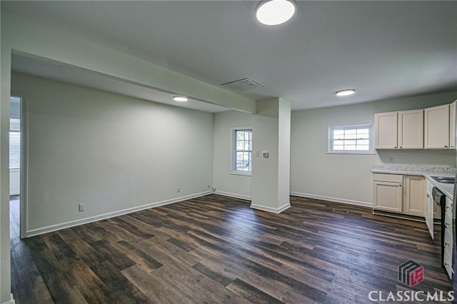 interior space with white cabinets, a healthy amount of sunlight, dark hardwood / wood-style flooring, and black dishwasher