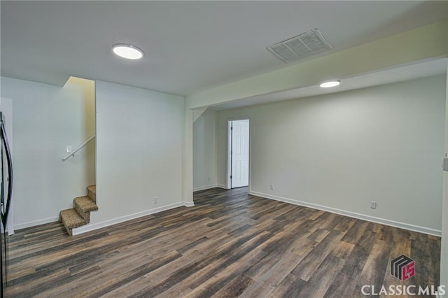 basement with dark hardwood / wood-style flooring and stainless steel refrigerator