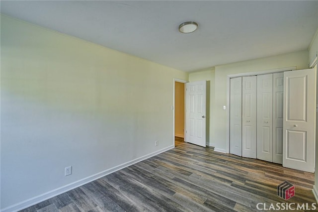 unfurnished bedroom with dark wood-type flooring and a closet