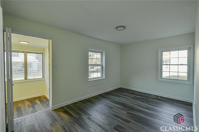 empty room with a wealth of natural light and dark wood-type flooring