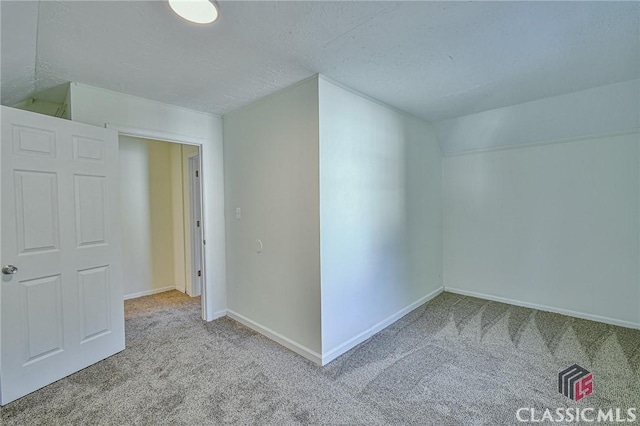 bonus room with light colored carpet and vaulted ceiling