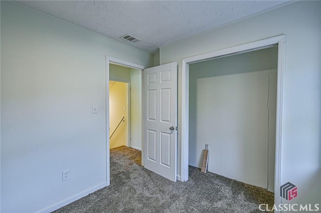 unfurnished bedroom with dark colored carpet and a textured ceiling