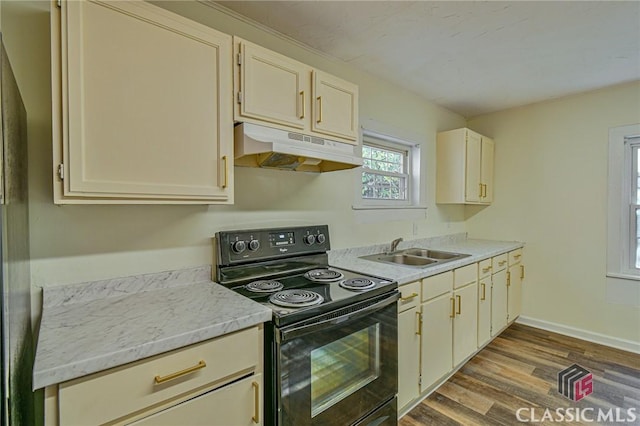 kitchen with cream cabinets, sink, black electric range oven, and hardwood / wood-style flooring